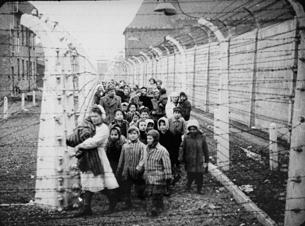 Surviving children of Auschwitz, including a set of twins, are led by relief workers and Soviet soldiers.